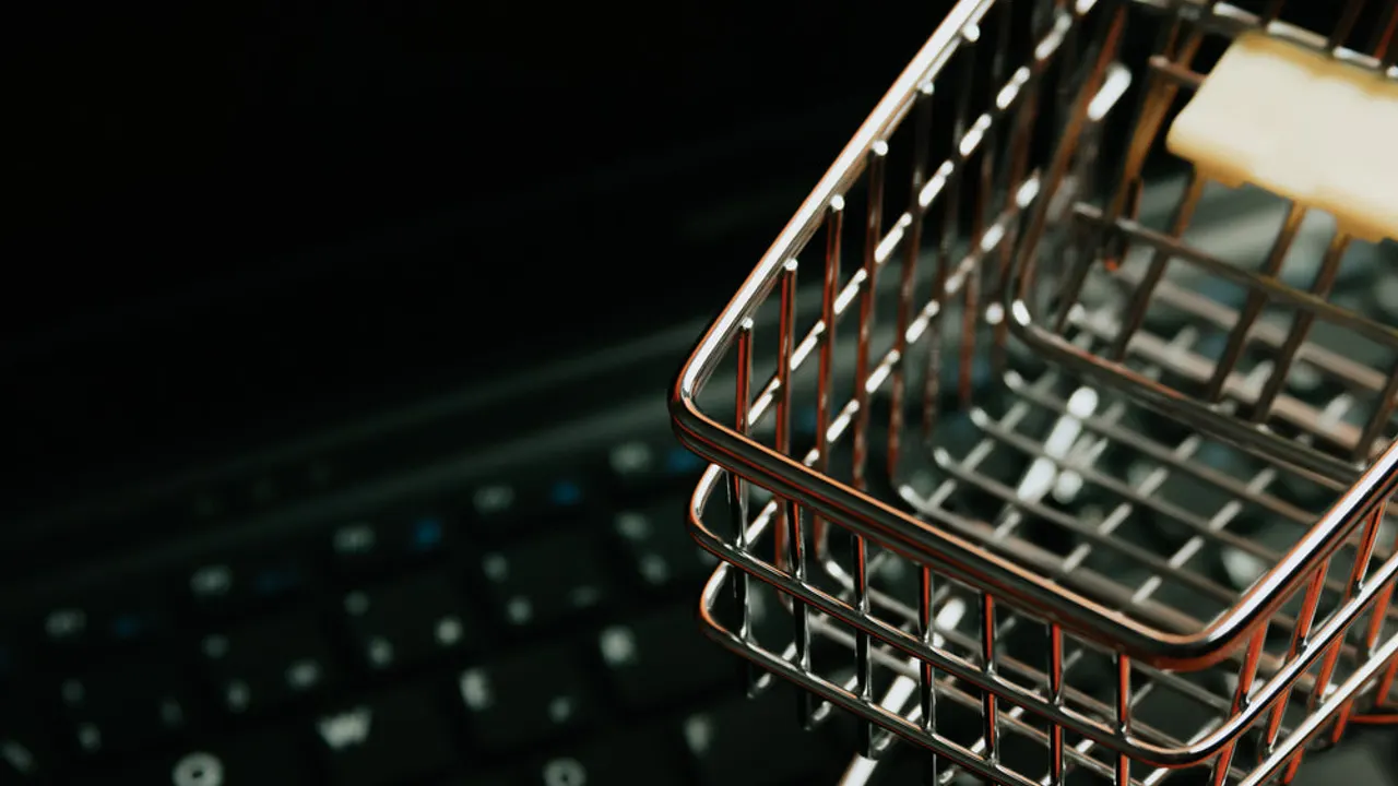 Miniature silver shopping cart on a black keyboard.