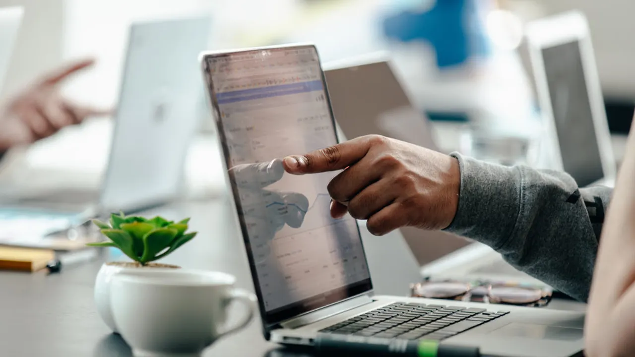 Man pointing at laptop screen analytics.